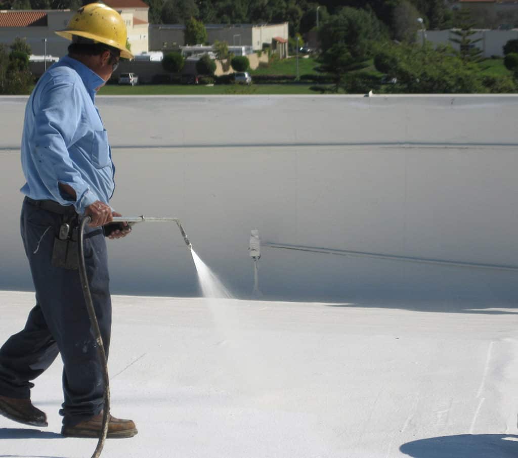 Spraying foam on roof with hardhat